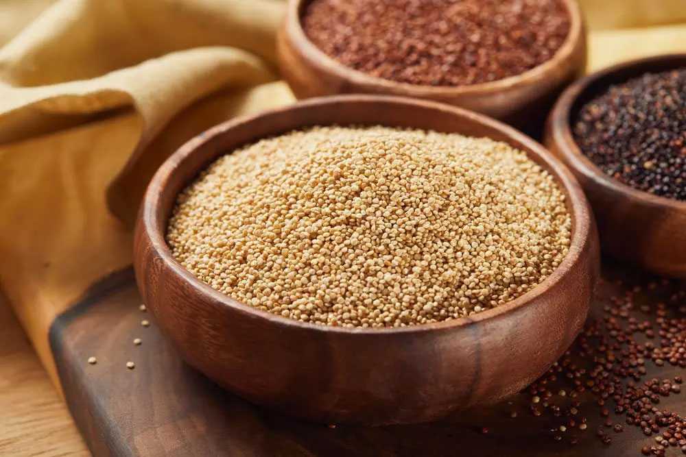 Why-a-Grain-Free-Diet A close-up of three wooden bowls filled with vibrant quinoa grains in beige, red, and black, showcasing a natural, wholesome, gluten-free option for healthy living and allergen-friendly meals.| Daré Vita Café | Las Vegas